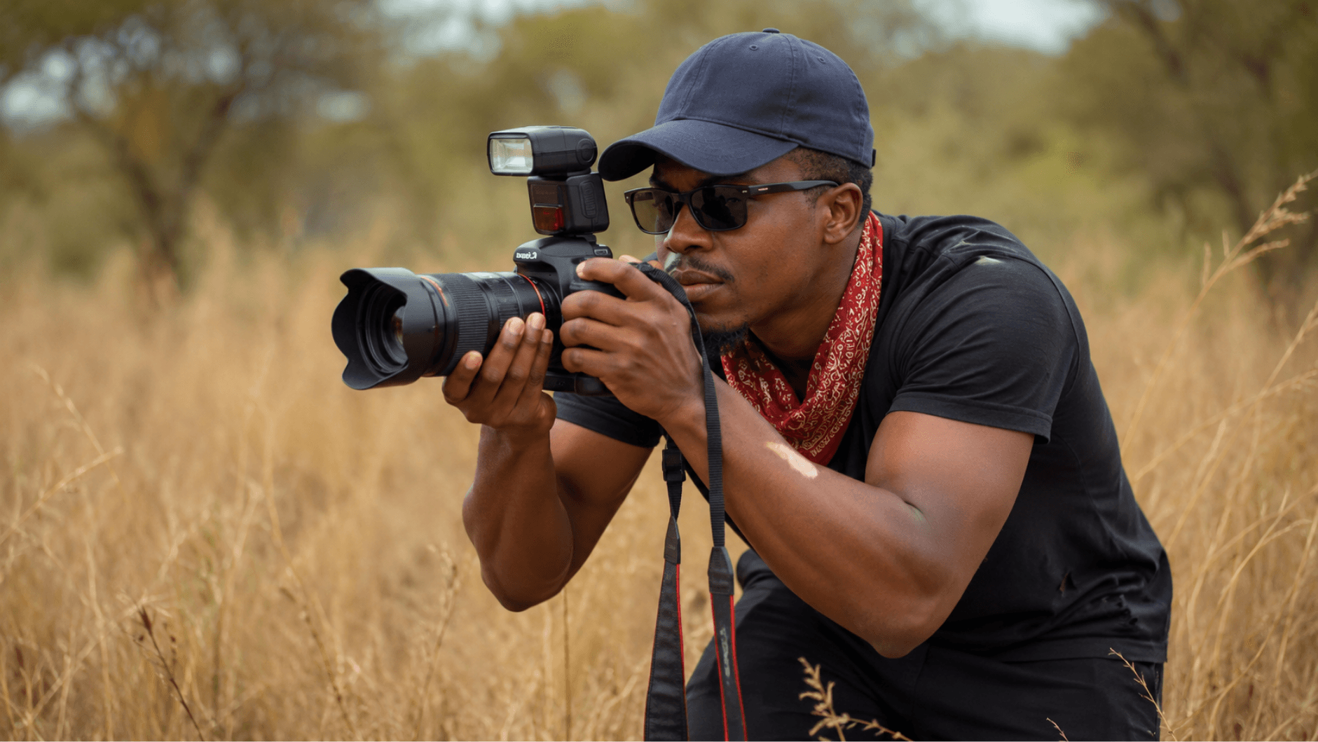 Photographer crouching in a field with a camera
